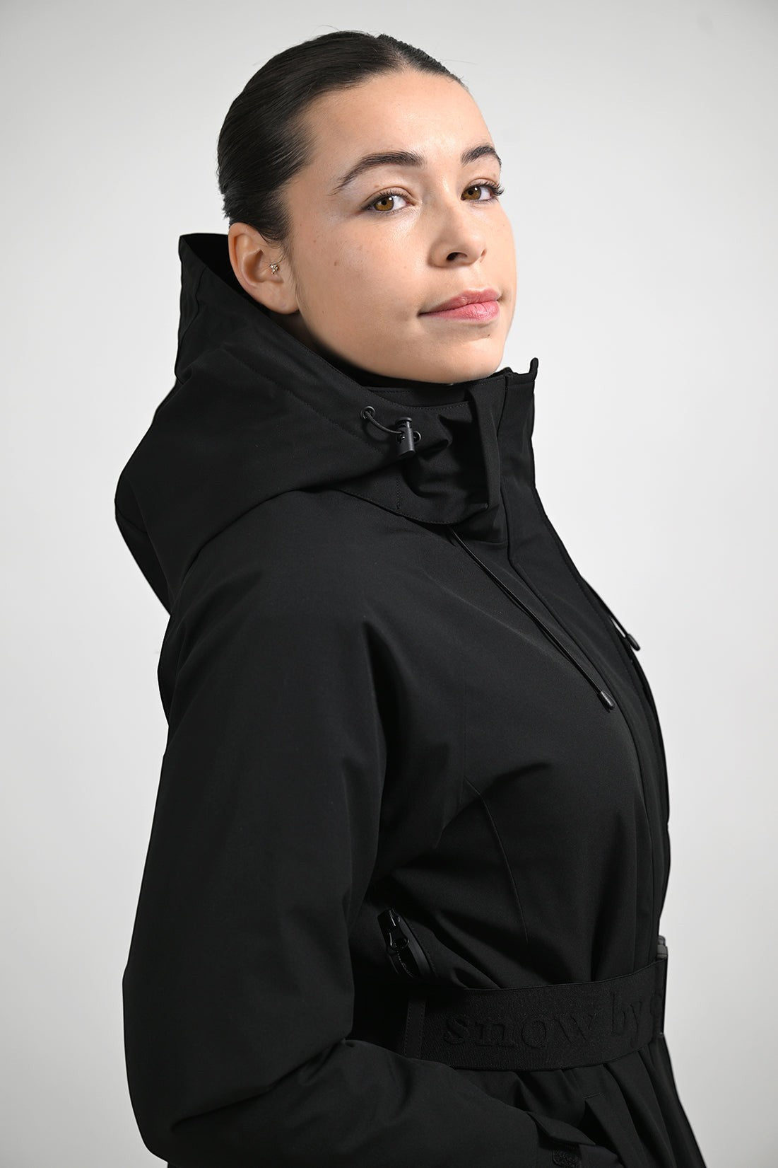 Snow by Clo black waterproof technical jacket with a removable hood, worn by a woman against a neutral background.